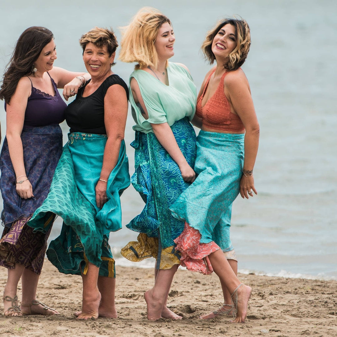 4 Models standing together on a the beach wearing maxi 100% sari silk skirts in blue.  