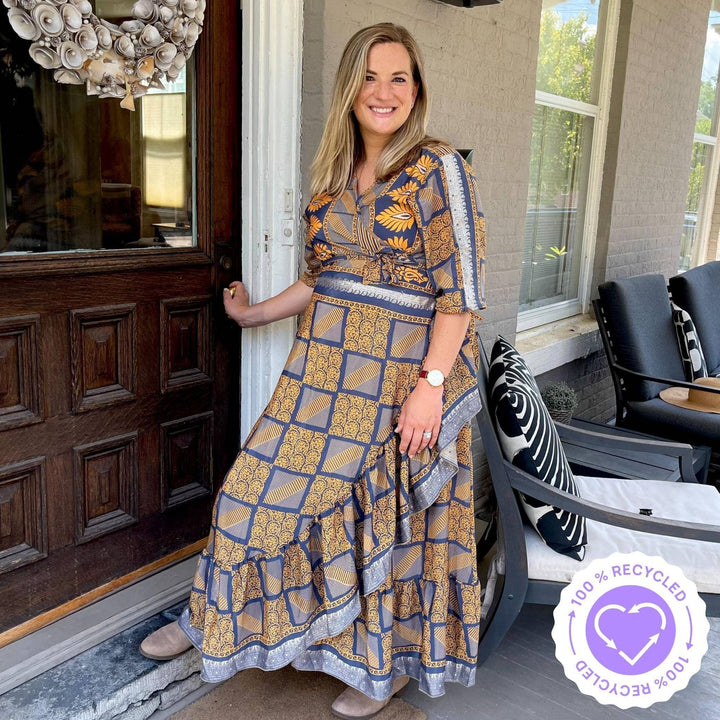 A pregnant mom entering her home. Wearing a wrap dress in neutral tones. Rich yellows and grays. Paired with a short tan bootie.