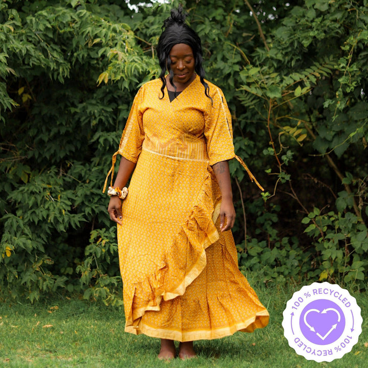 A woman dancing in a park in a golden yellow Zaria Wrap Dress.
