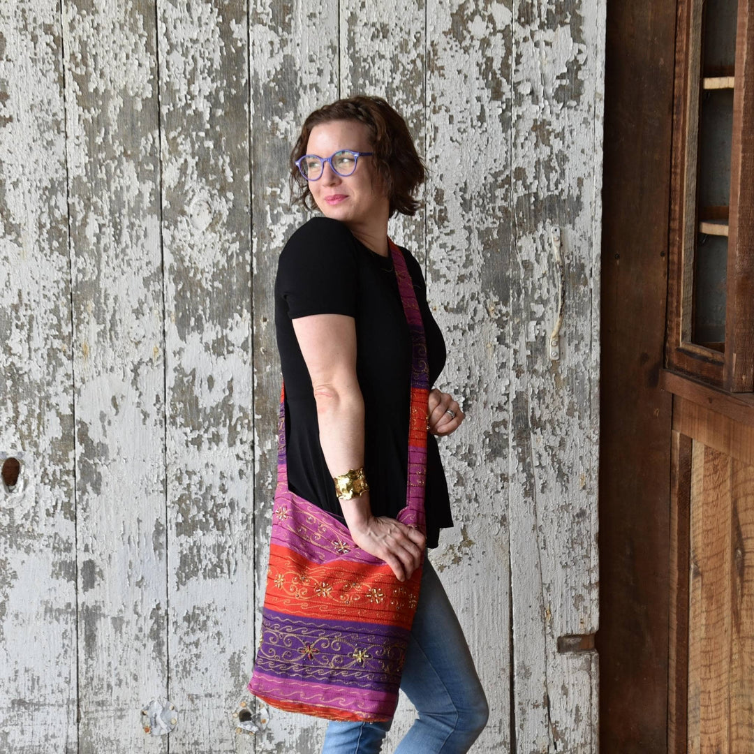 Model wearing Morocco Sunset Boho Sling Crossbody Bag in front of a distressed wooden wall. 