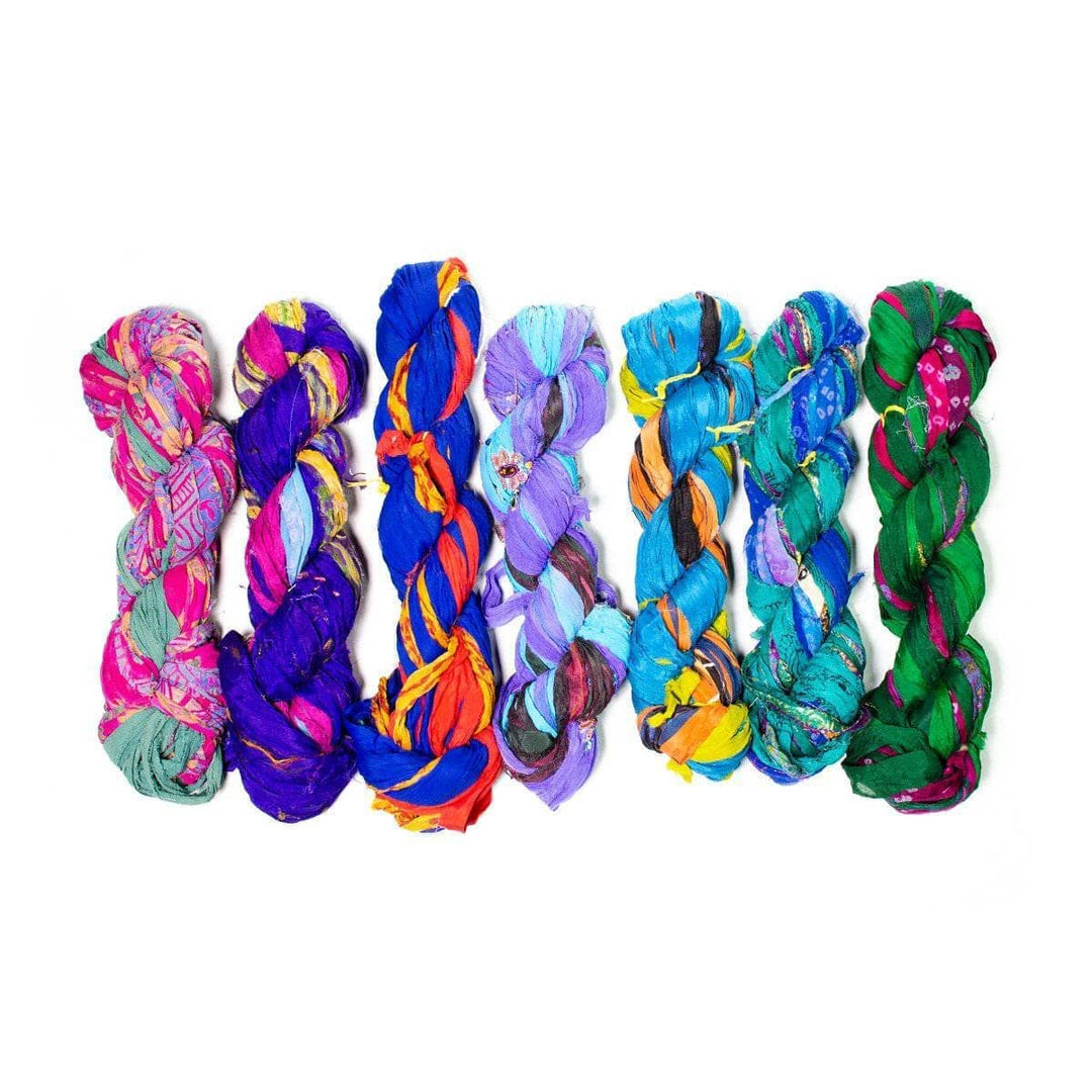 chiffon ribbon yarn assortment of jewel tone skeins (all one of a kind) in front of a white background.