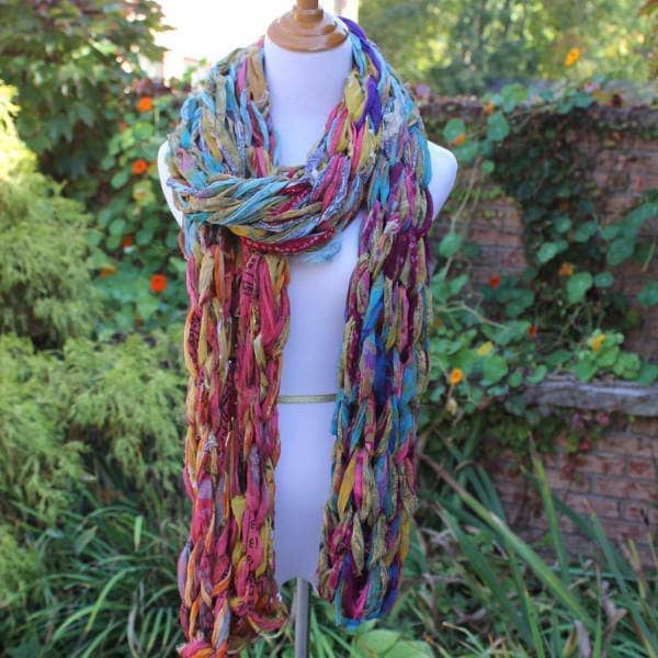 Mannequin wearing 30 Minute Arm Knit Scarf standing in greenery