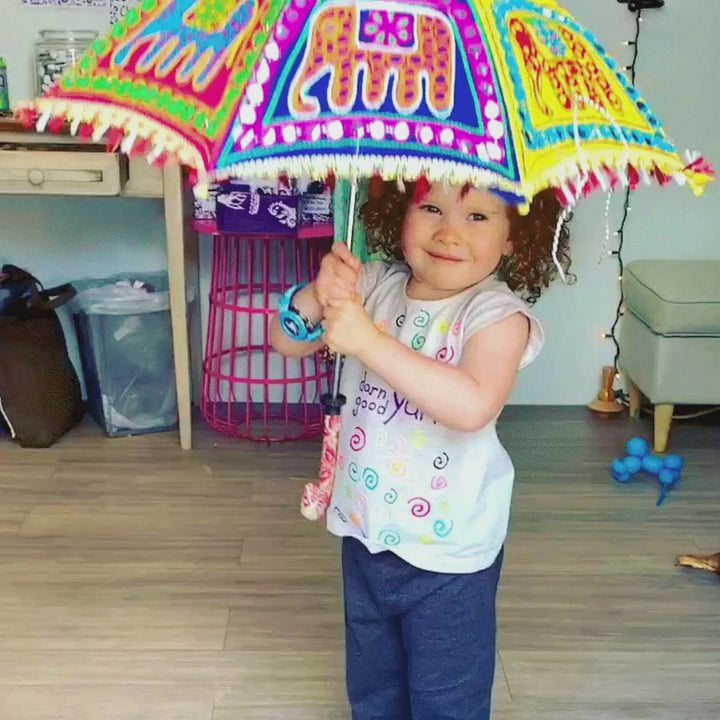 Video of little model hiding under an embellished parasol umbrella with elephants on it.  