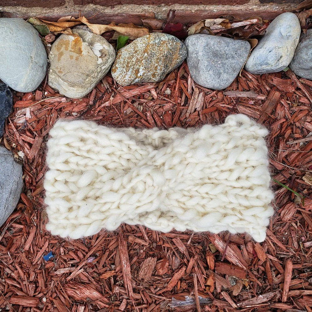 A white chunky headband outside laying on brown mulch