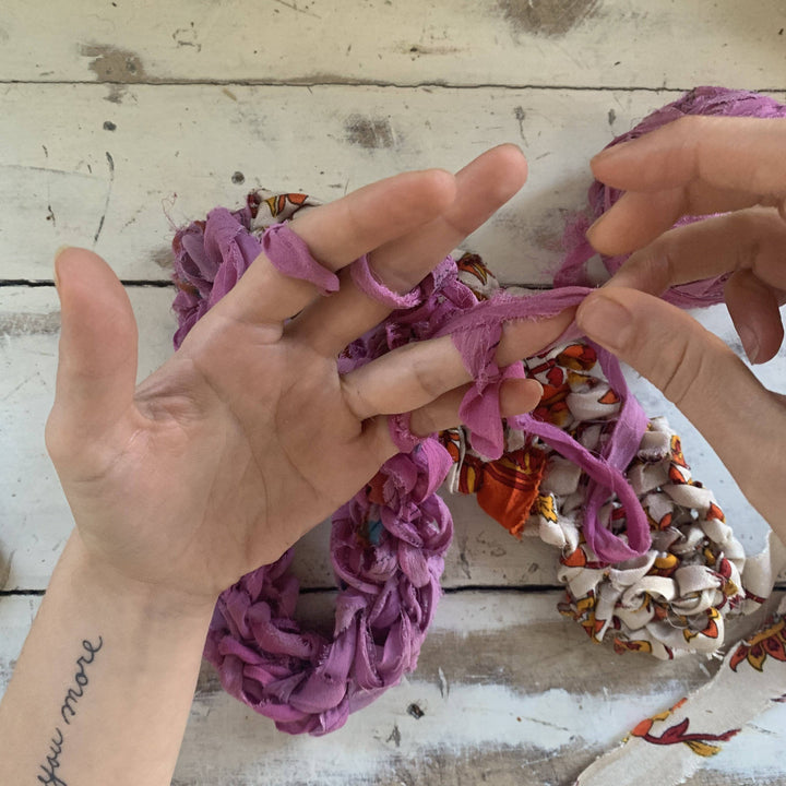 in progress photo of finger knit infinity scarf in front of distressed wood background.