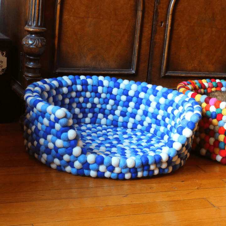 An up close of the blue felt bal pet bet on a wood floor.