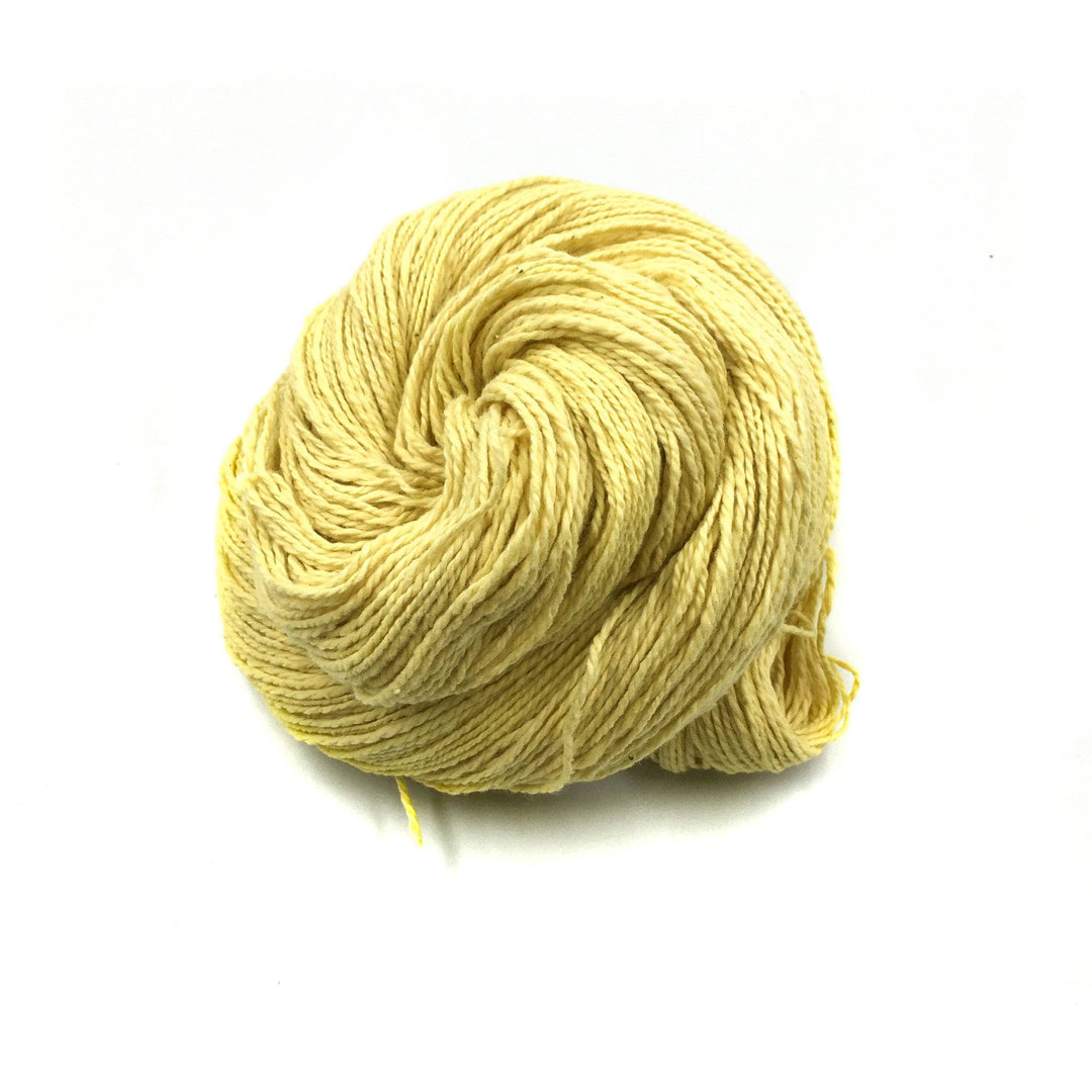 close up of yarn in the color fresh cosmos (yellow) with a white background