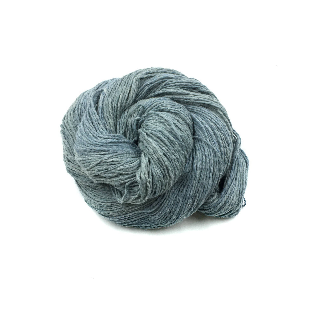 close up of yarn in the color indigo (grey) with a white background