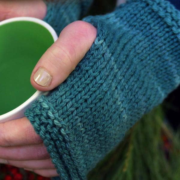 Model wearing blue Cestari Fingerless Knit Mittens and holding a green and white coffee cup