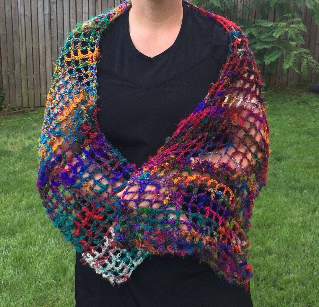 woman standing outdoor with a colorful shawl in her arms 