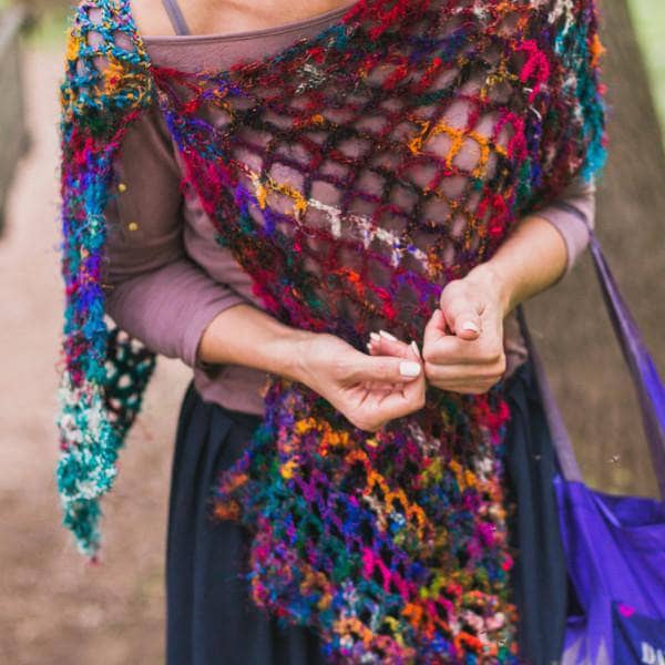 woman standing outdoor with a colorful shawl in her arms 