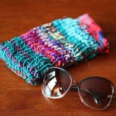 A Home for My Sunnies knit glasses case sitting next to sunglasses on a wooden surface