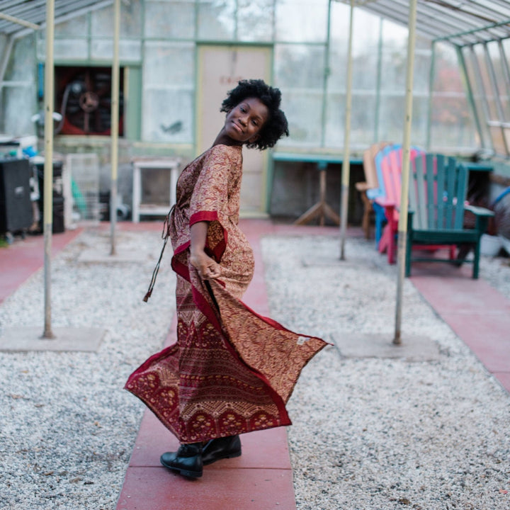 Model is twirling in a greenhouse wearing a red long aanya kaftan.  