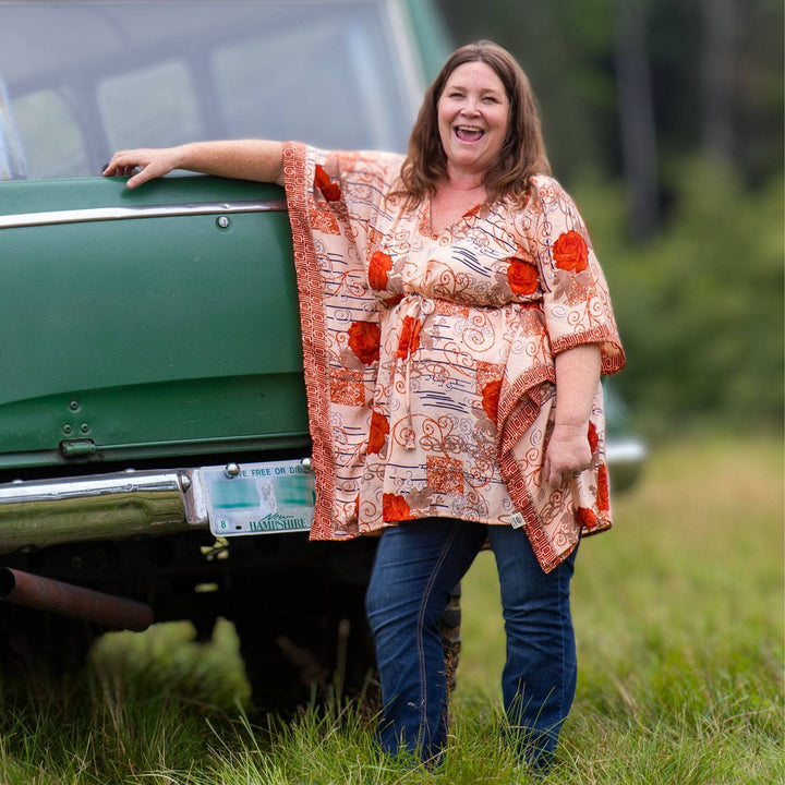 woman leaning on car wearing orange rose colored short tunic