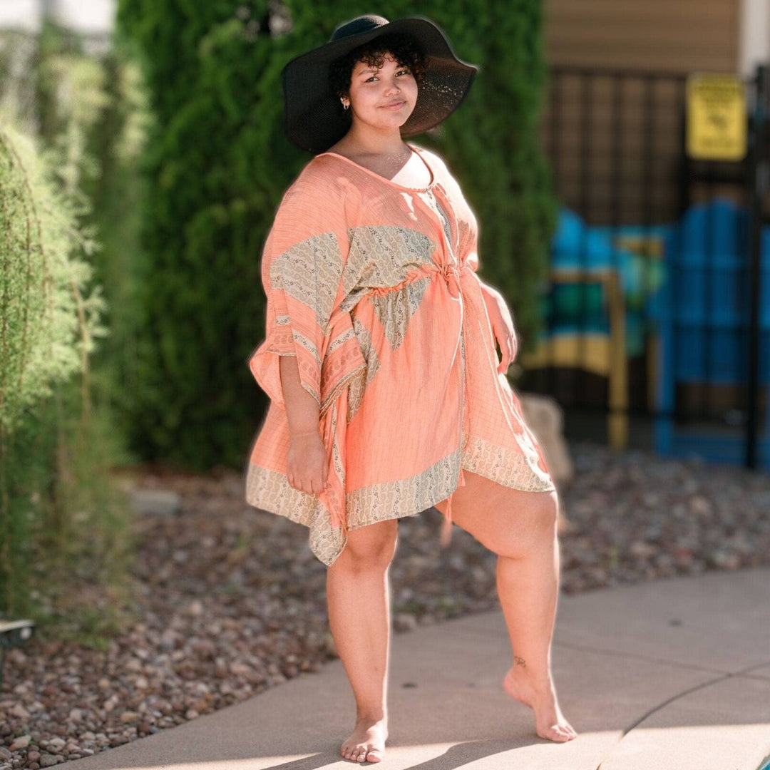 woman standing by pool wearing peach kaftan tunic