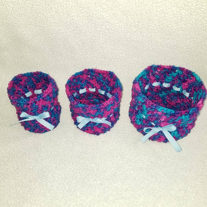 three blue, pink and purple yarn basket holders on a white background
