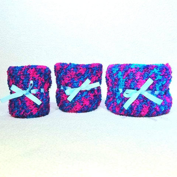 three blue, pink and purple yarn basket holders on a white background