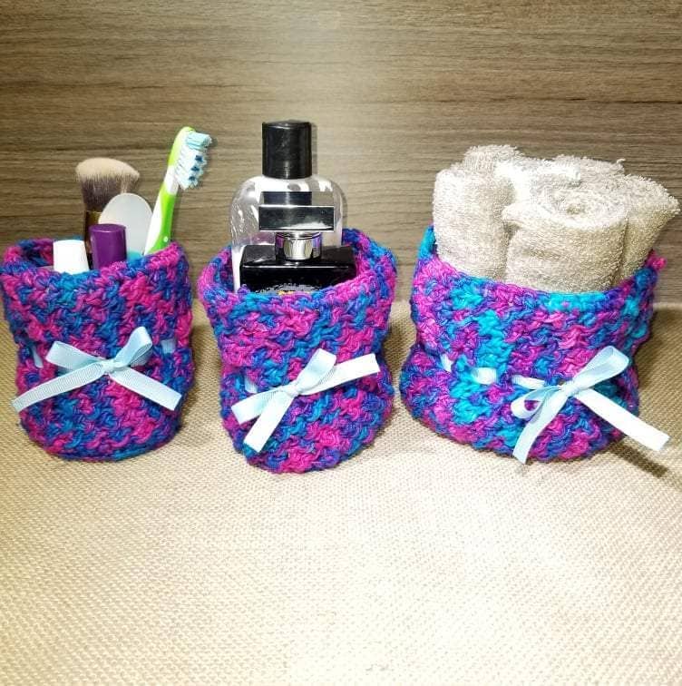 three blue, pink and purple yarn basket holders on a wood background