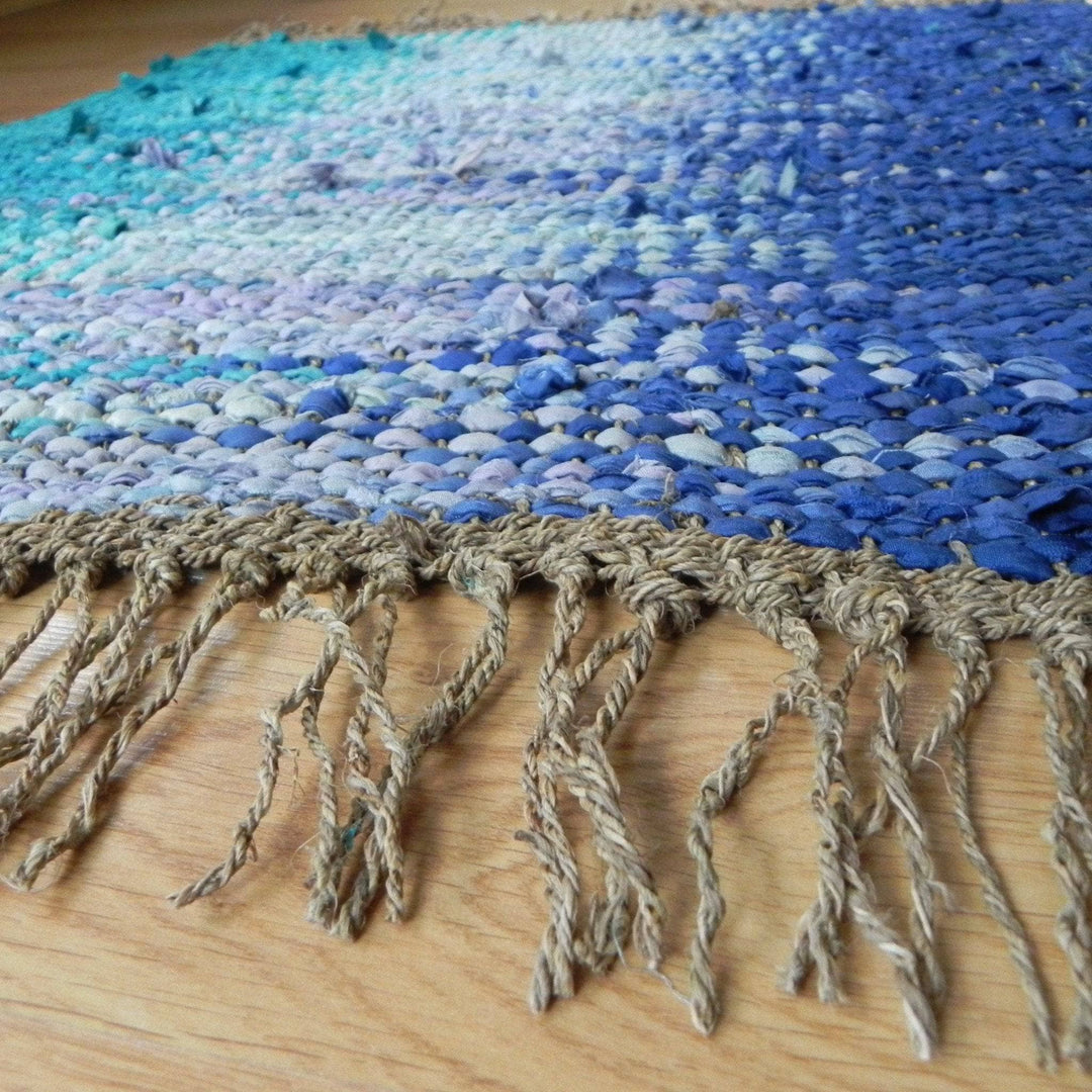 Close up view of the Adriatic Pools woven rug in blues sitting on a wooden surface