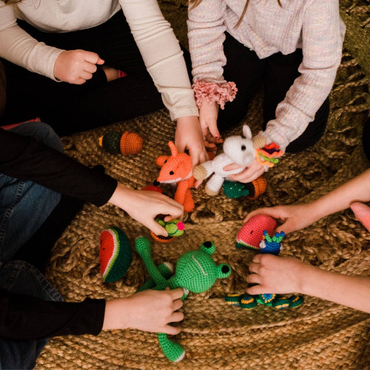 Closeup of kids sitting and playing with stuffed amigurumi toys.