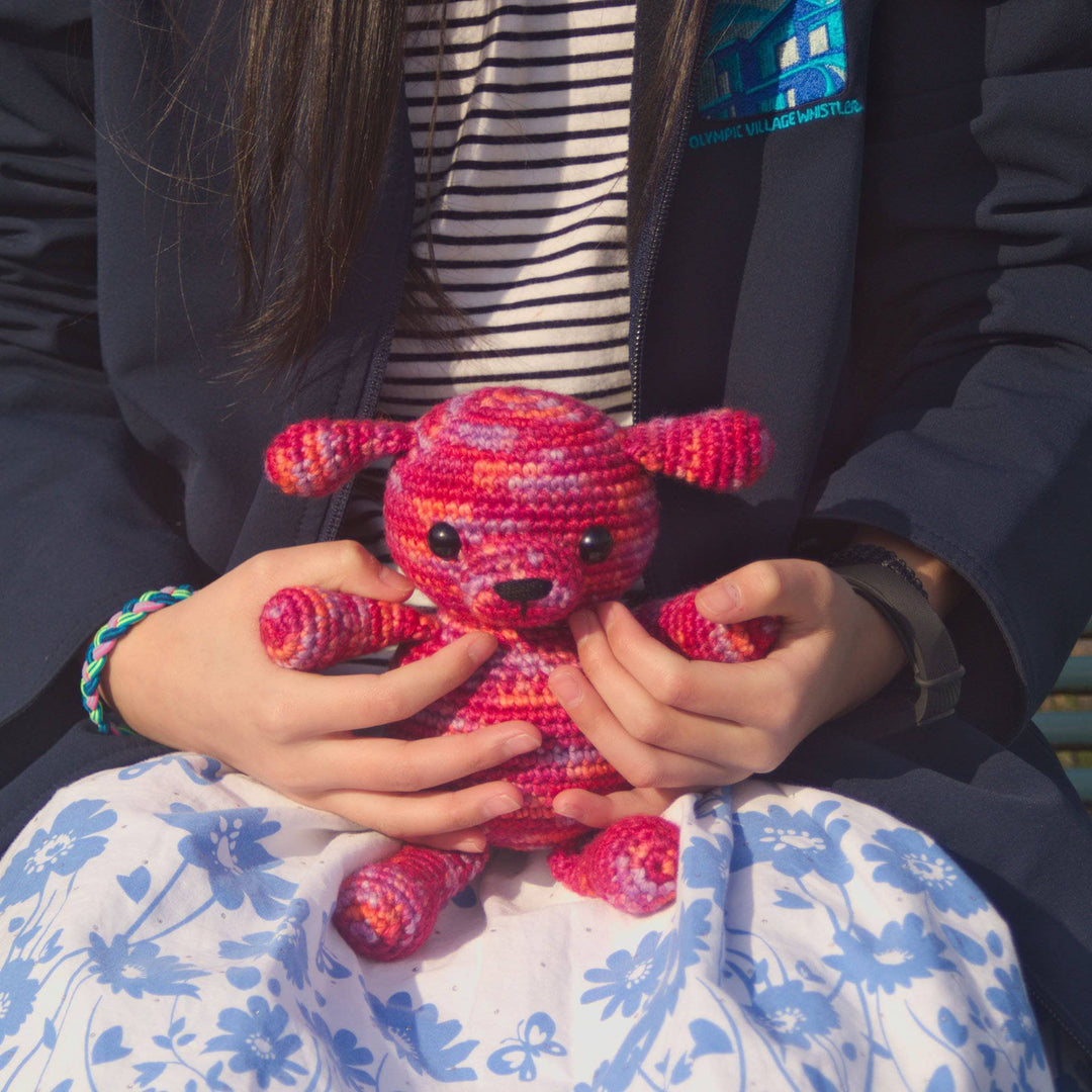 Young girl holding an Amigurumi Puppy crocheted in Raspberry (pinks)