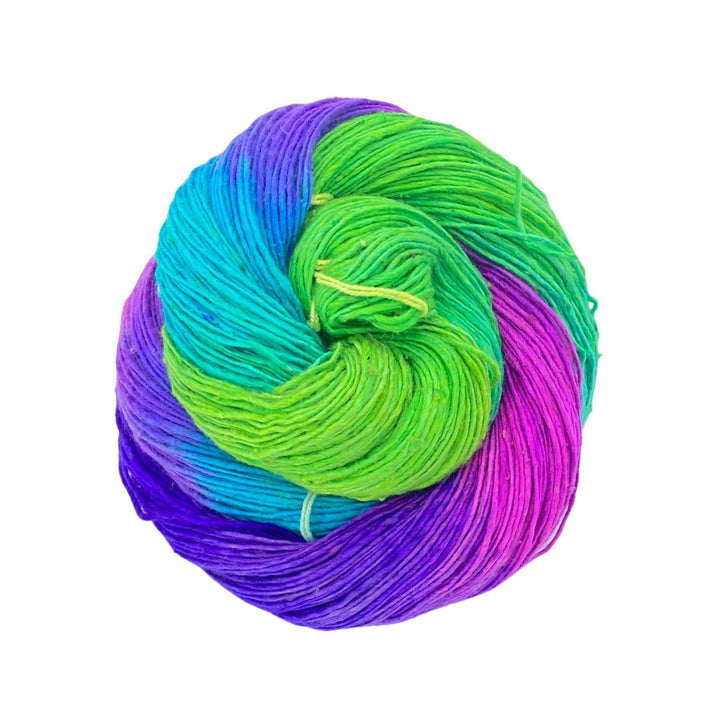 skein of lace weight silk yarn in front of a white background. Purple, magenta, blue, green variegated.