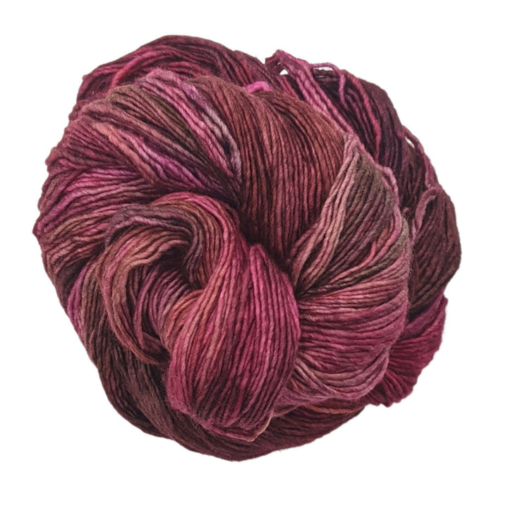 skein of tonal purple/red wool yarn in front of a white background.