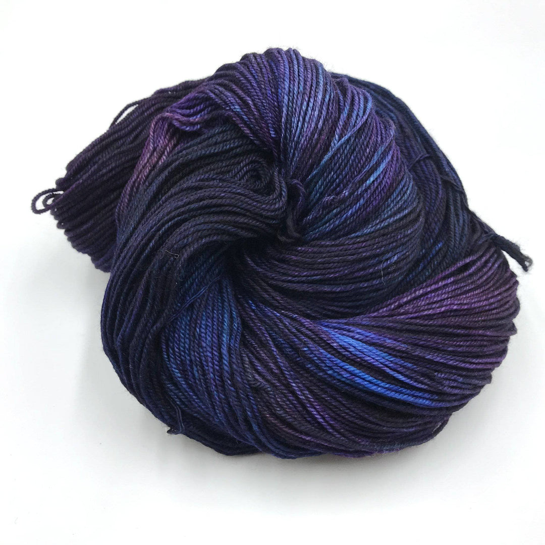 skein of tonal blue, purple and navy yarn in front of a white background