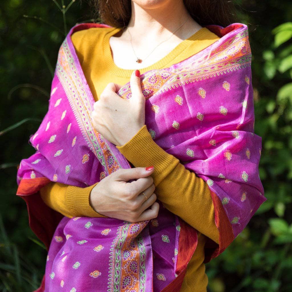 Woman wearing an Artisan Made Sari Silk & Cotton Scarf in pink colors and standing in front of greenery