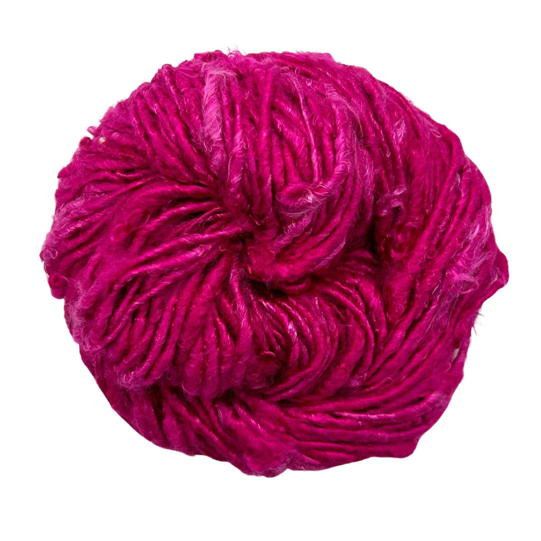 Top view of skein of Fuchsia banana fiber yarn curled into a birds nest shape in front of a white background.