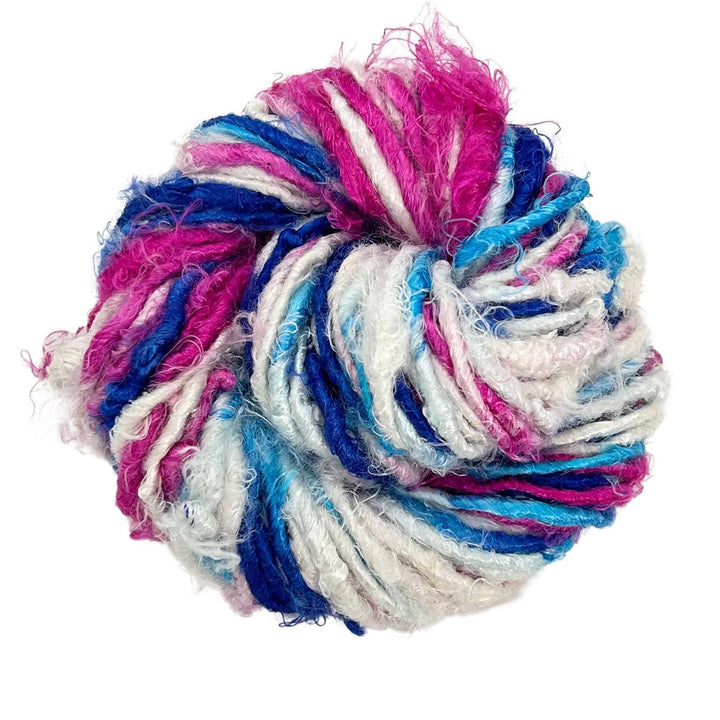 Top view of skein of Mulberry Swirl banana fiber yarn curled into a birds nest shape in front of a white background.