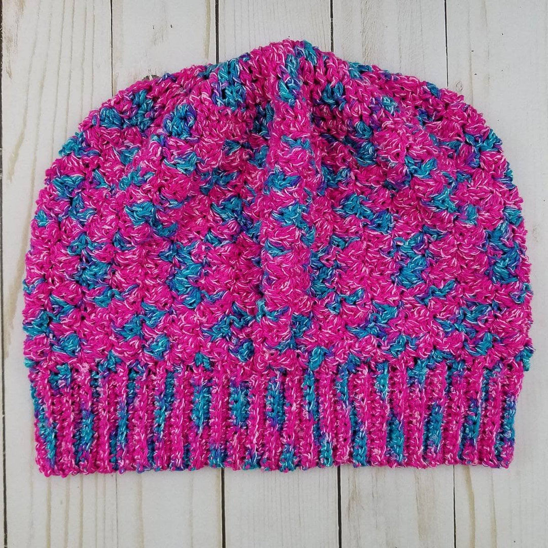 Berry Nice Slouchy Beanie Crochet hat in pink and blue laying on a wooden surface