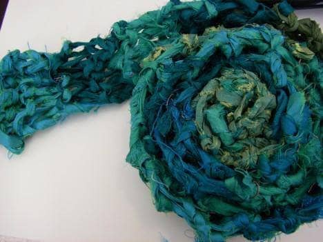 Teal crochet scarf laid on a white background