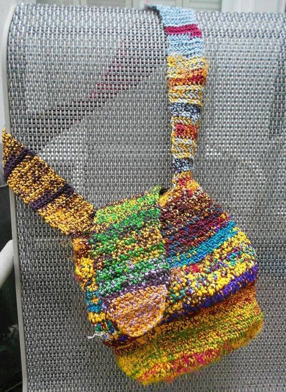 Yellow crossbody crochet bag draped over a silver bench