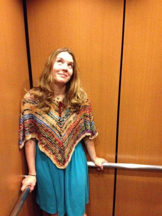 Woman in elevator wearing a blue dress and brown shawl