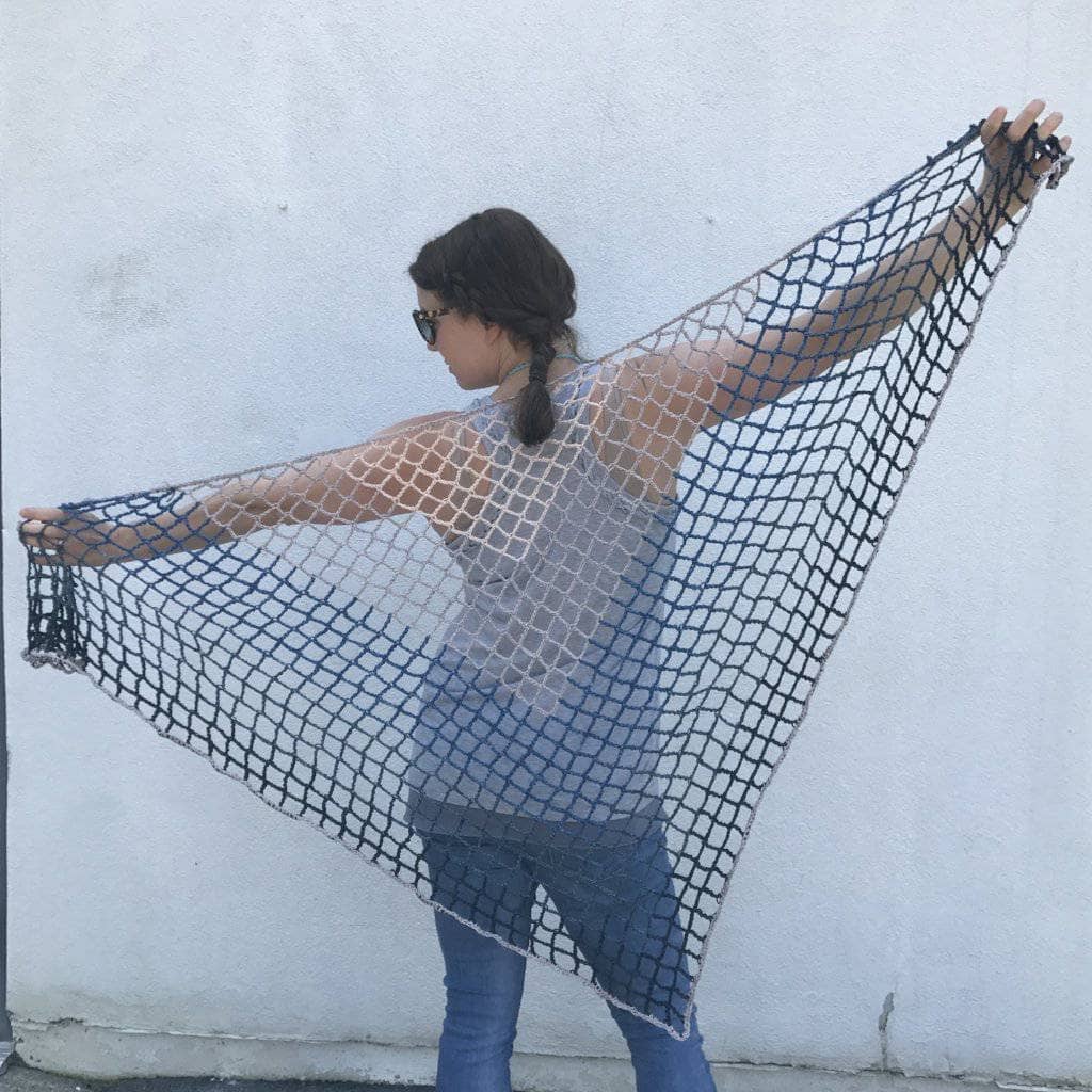 Woman holding a Blue Jay Triangle Scarf behind her back and standing in front of a white wall