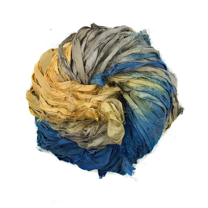 a skein of blue, yellow, and silver ribbon yarn on a white background