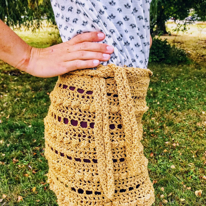 A woman wearing a beige crocheted skirt outside