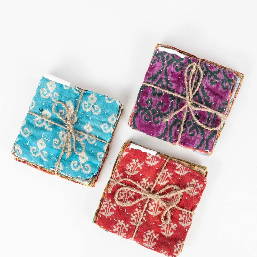 Three four-packs of kantha coasters tied up with twine on a white background.