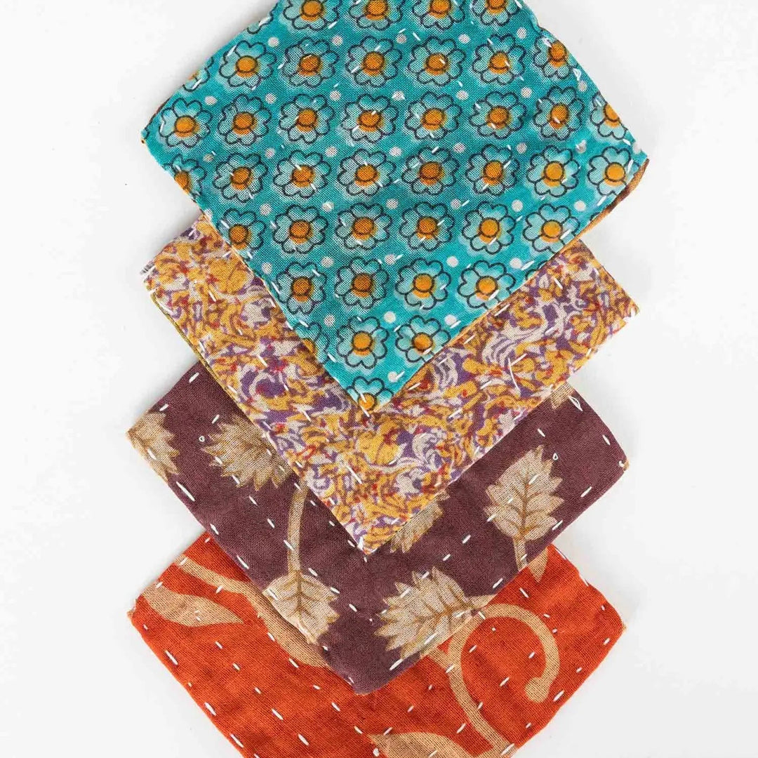 Four kantha coasters laid on top of one another on a white background.
