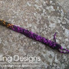 Purple Braided Bracelet laying on a concrete background