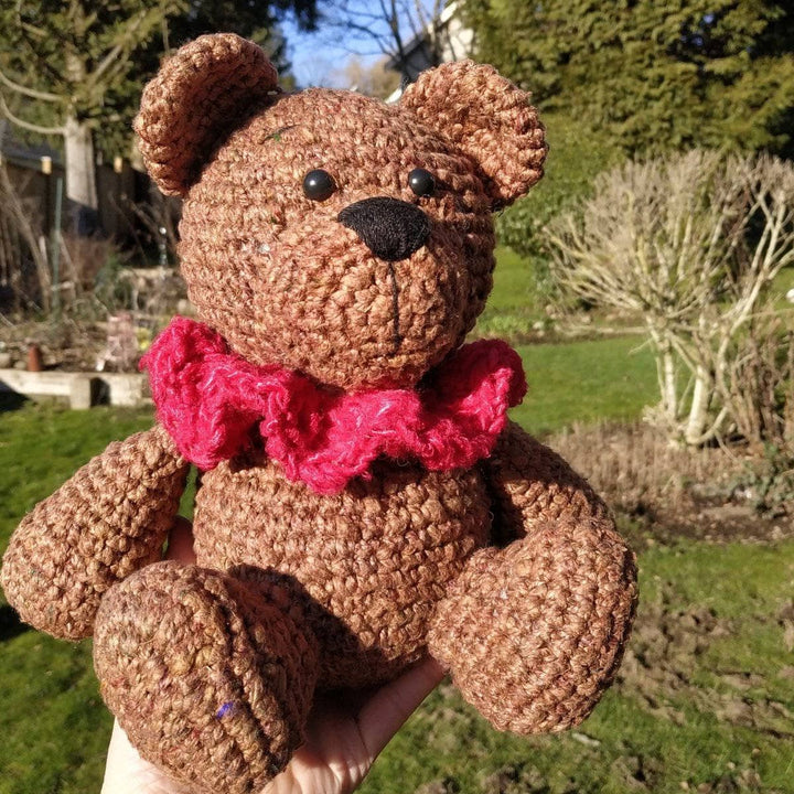 Brown Bear Amigurumi Crochet stuffed animal sitting on a hand over grass