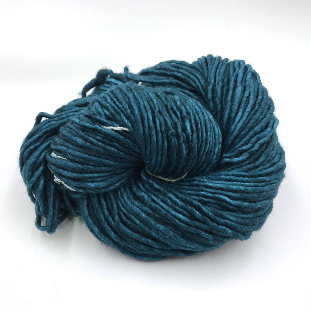 A deep teal blue skein of yarn on a white background