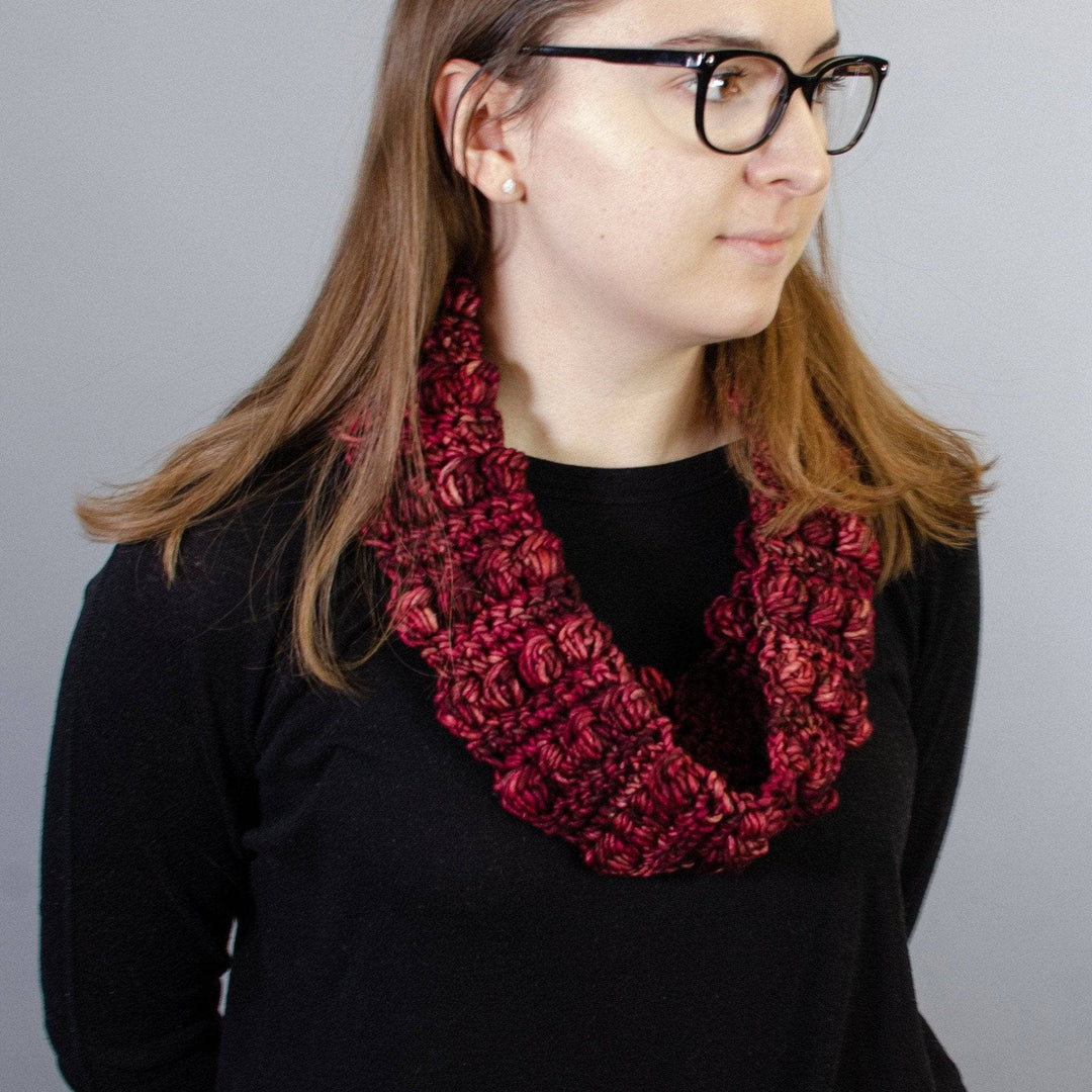 A women wearing a black shirt with a red infinity scarf around her neck 