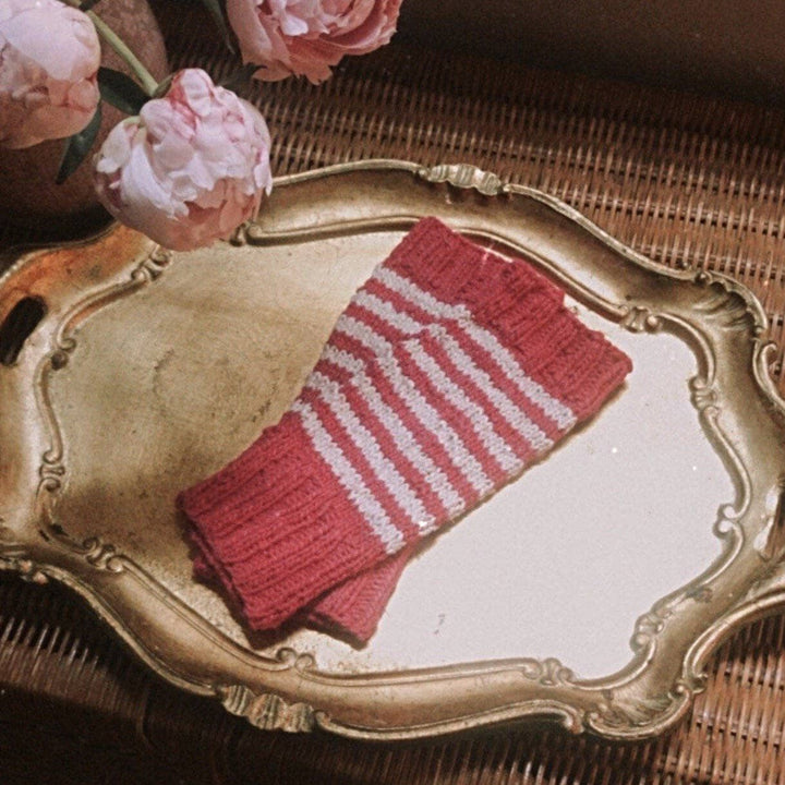 pink and white stripped glove laying flat on a gold plate