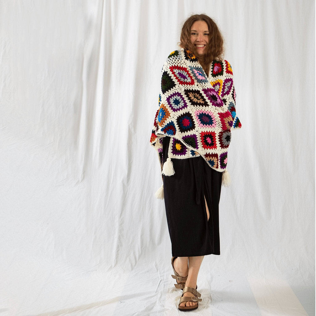 Founder Nicole wrapped up in granny square shawl in front of a white background. 