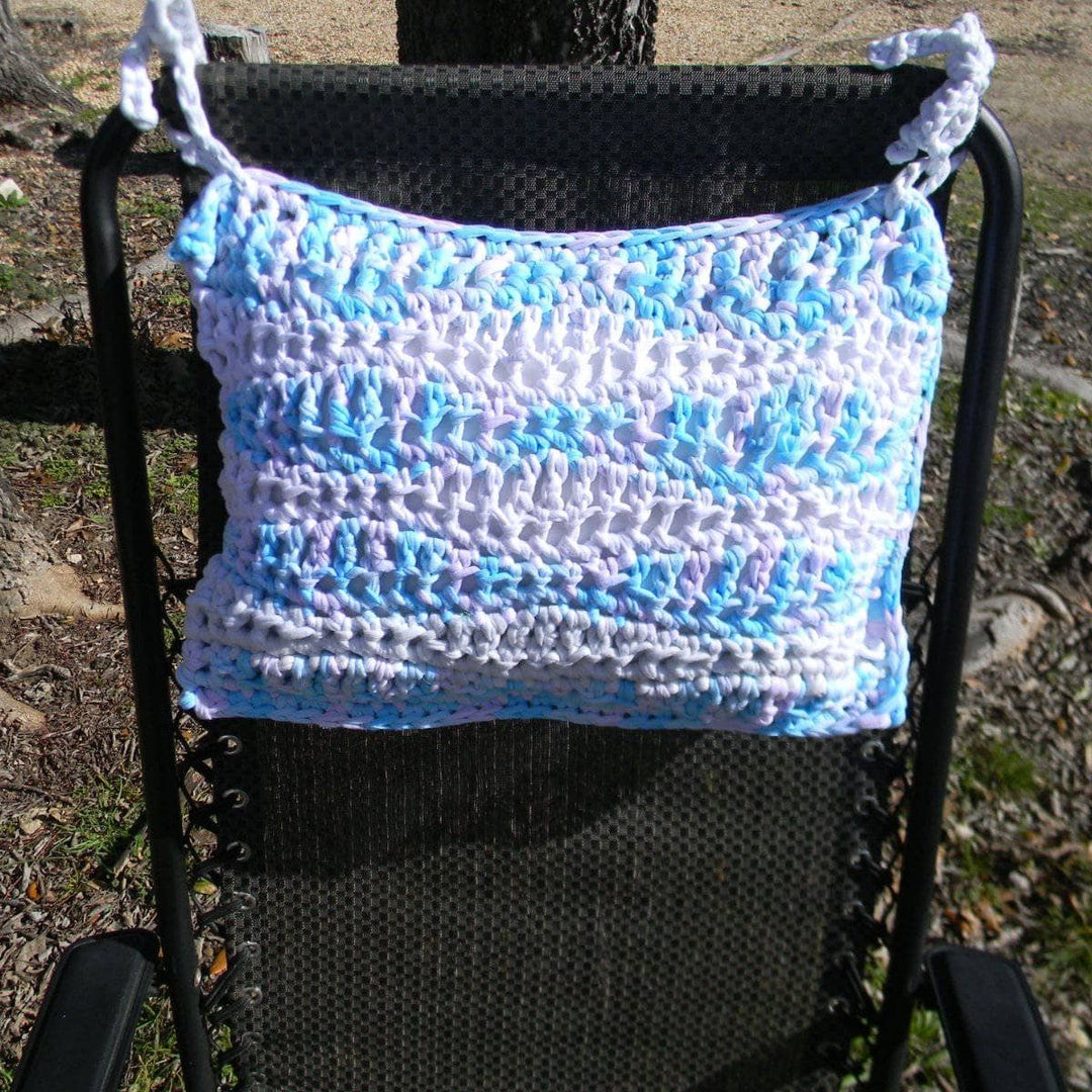 Blue and lavender crocheted Cast Away pillow tied to a black outdoor chair