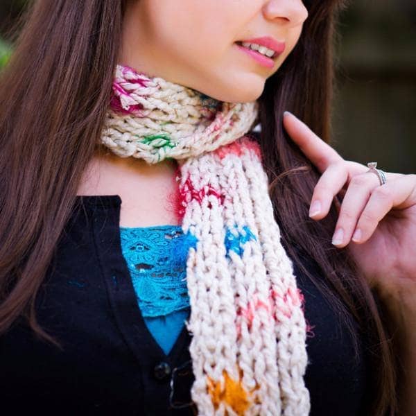Woman in the woods wearing a multicolored knit Celebration scarf