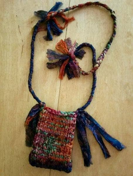 Small Cell Phone Shoulder Bag knit from multicolored yarn sitting on a wooden surface