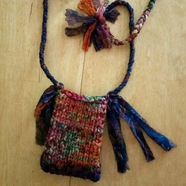 Small Cell Phone Shoulder Bag knit from multicolored yarn sitting on a wooden surface
